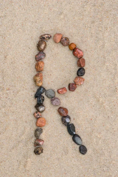 Kieselstein r Buchstabe auf Sand — Stockfoto