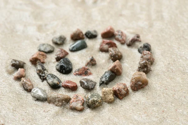 Símbolo de hélice de seixo em foco seletivo de areia — Fotografia de Stock