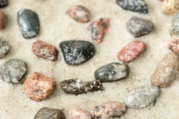 Símbolo de hélice de seixo em foco seletivo de areia — Fotografia de Stock