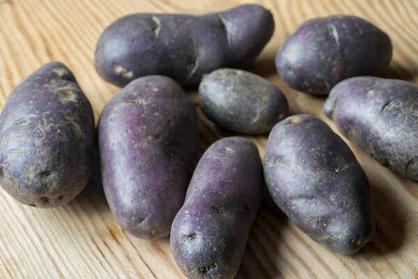 violet potatoes on wooden background closeup