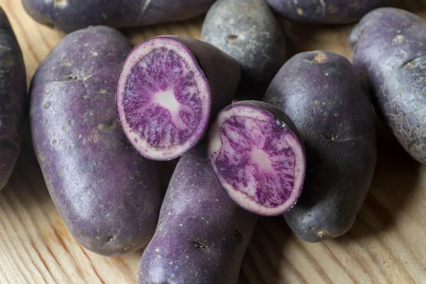 Violet potatoes on wooden background closeup — Stock Photo, Image