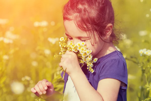 Kleines Mädchen schnuppert Blumen — Stockfoto