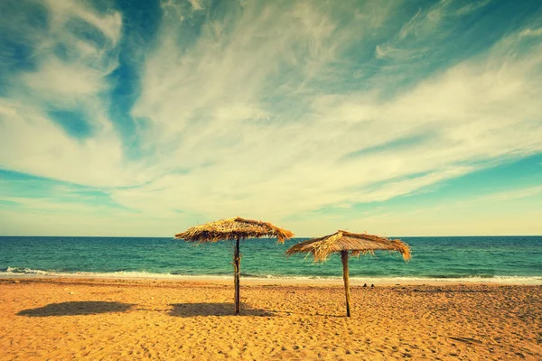 Due ombrelloni di paglia sulla spiaggia sabbiosa — Foto Stock