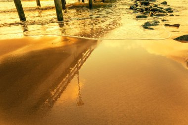 Altın gün batımında sahilde iskele yansıma