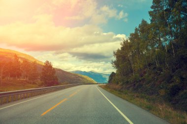 Dağ yolu ile bulutlu gökyüzü gün batımında