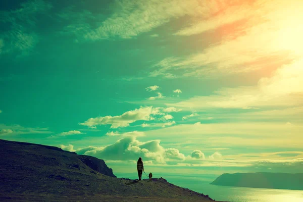 Silhouette Von Junger Frau Und Hund Gegen Meeresfjord Bei Sonnenuntergang — Stockfoto