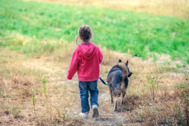 Mutlu küçük kız ile köpek alanına yürüyor. Köpeğin tasmasını tutan kız kameraya geri. Village adlı kız