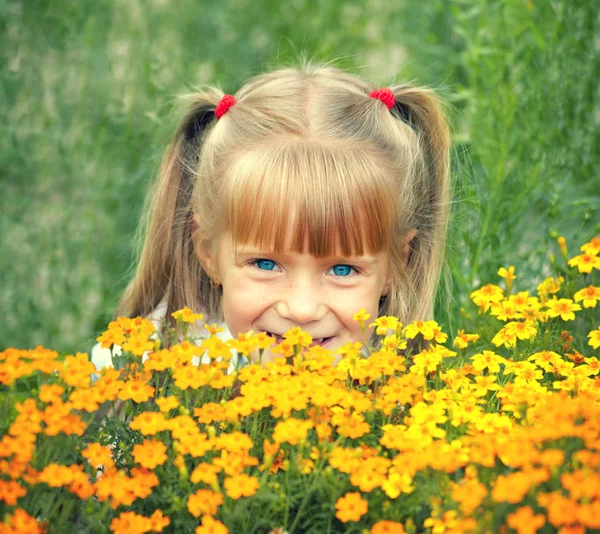 夏の庭の花の後ろに隠れている幸せ笑顔の少女 — ストック写真