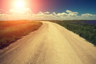 Gün batımında mavi gökyüzü ile toprak yol. Güzel bir akşam doğa