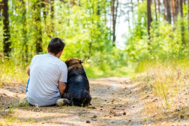 Bir adam ile Orman yolundaki bir köpek oturuyor