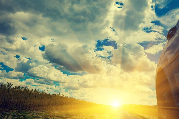 Bir alandaki bir kırsal toprak yolda bir araba. Gün batımını giden yol