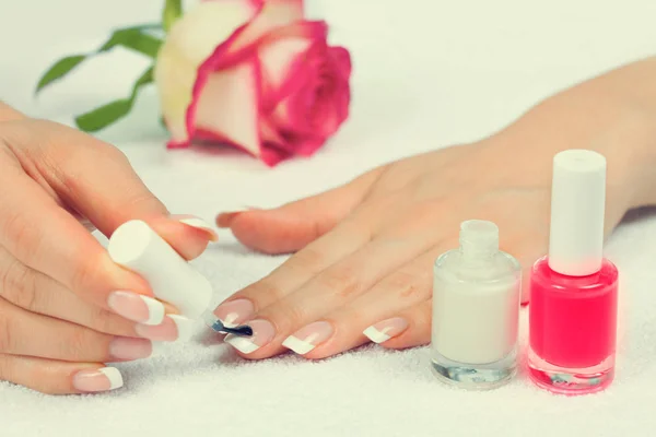 Mujer aplicando esmalte de uñas para una perfecta manicura francesa sobre blanco —  Fotos de Stock
