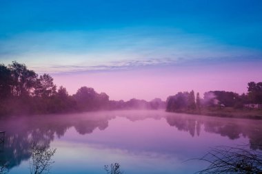 Sabah erkenden, göl üzerinde şafak. Sakin göl güneş doğmadan önce. Puslu bir sabah, bir kırsal manzara, bir çöl, mistik bir duygu
