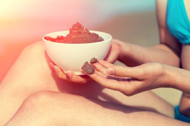 Genç kadın çamur maskesi sahilde vücudunda bulaşması. Dead sea çamur spa uygulamaları için bir fincan tutan kadın