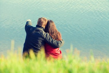 Sahilde oturan ve denizde seyir aşık genç Çift