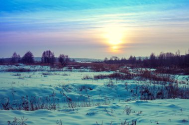 Kış manzarası. Kırsalda bir akşam. Gün batımında, karla kaplı güzel bir gökyüzü var. Sihirli ışığı olan kırsal alan.
