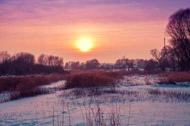 Kış manzarası. Kırsalda bir akşam. Gün batımında, karla kaplı güzel bir gökyüzü var. Sihirli ışığı olan kırsal alan.