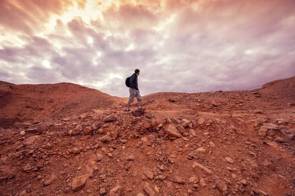 Human hiking in a desert. Desert landscape with dramatic cloudy sky