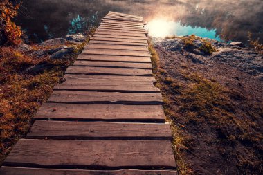 Gölün üzerinde büyülü bir gün doğumu. Göl kıyısındaki tahta güvertede. Sabahın erken saatlerinde sakin bir göl. Doğa manzarası