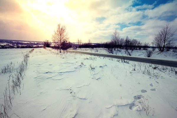 Sunset in the countryside. The country road along the snow-covered field