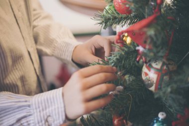 Bir çocuk, Noel tatili süslemesi için annesine yardım eder.