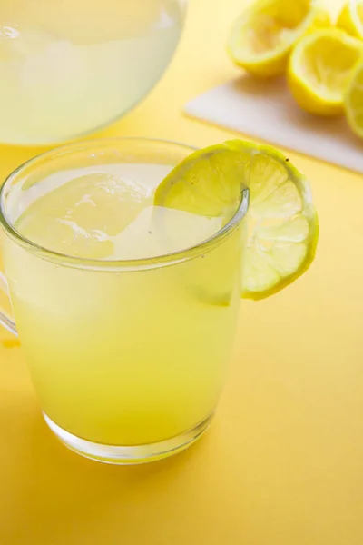 Agua y limón en fondo amarillo —  Fotos de Stock