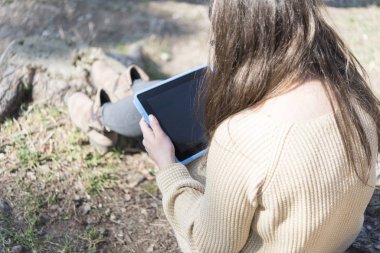 Gözlüklü mutlu kadın parkta tablet tablet kullanıyor.