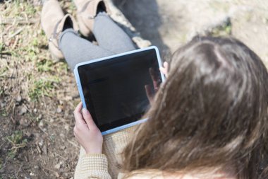 Gözlüklü mutlu kadın parkta tablet tablet kullanıyor.