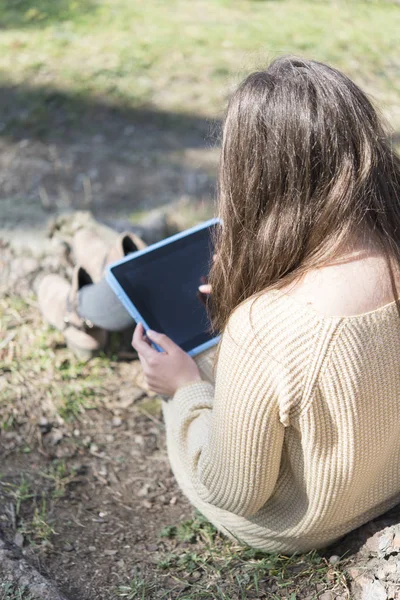 Счастливая женщина в очках с планшетным компьютером в парке — стоковое фото