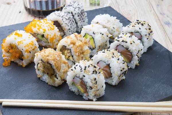 Rollos de sushi en un plato de pizarra — Foto de Stock