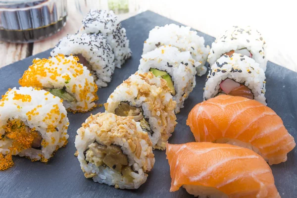 Rollos de sushi en un plato de pizarra — Foto de Stock