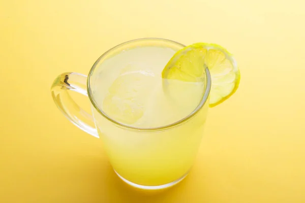 Water and lemon in yellow background — Stock Photo, Image