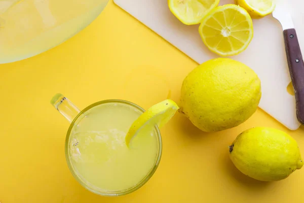 Agua y limón en fondo amarillo —  Fotos de Stock