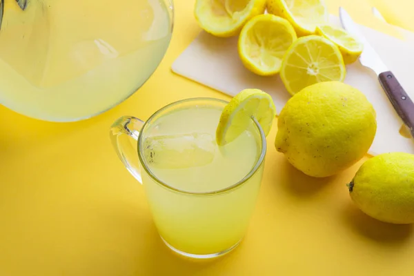 Water and lemon in yellow background — Stock Photo, Image