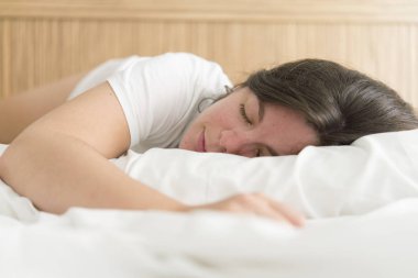 Genç ve güzel bir kadın yatakta uyuyor.