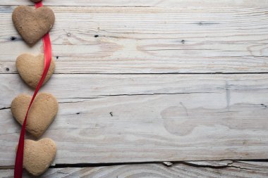 Kurabiyeler ve kalp şeklinde kırmızı kurdele ahşap arka planda