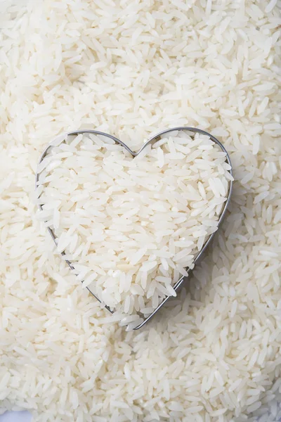 Arroz en tazón de corazón sobre fondo de arroz blanco — Foto de Stock