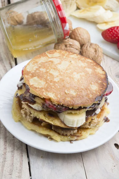 Pannenkoeken met banaan, noten en aardbeien op houten ondergrond — Stockfoto