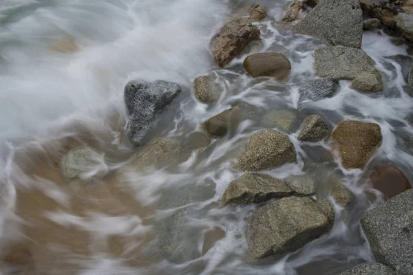 Ondas colidem com um litoral rochoso e acidentado em uma manhã nublada — Fotografia de Stock