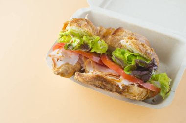 Sandviç kruvasan, marul, domates ve füme hindi.