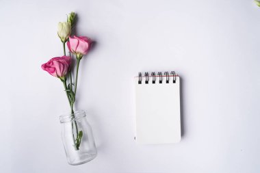 Çiçekler pembe Eustoma beyaz ve defter üzerinde basit vazo 