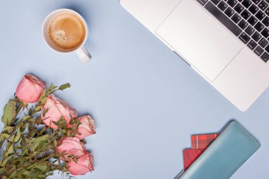 düz dizüstü bilgisayar, kahve fincanı, pembe güller ve mavi arka planda kartları olan cüzdan. 