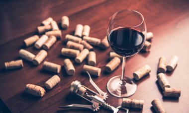 Kırmızı şarap cam, mantarlar ve tirbuşon ahşap tablo.