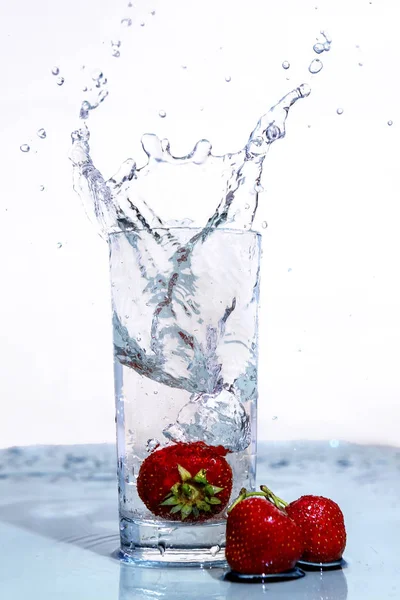Fresas caen en un vaso de agua . — Foto de Stock