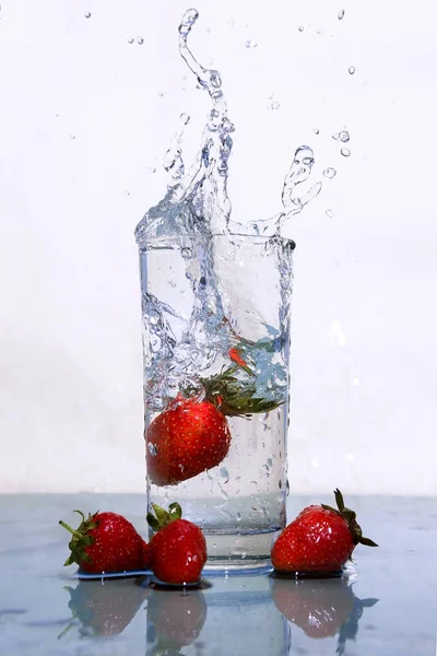 Le fragole cadono in un bicchiere d'acqua . — Foto Stock
