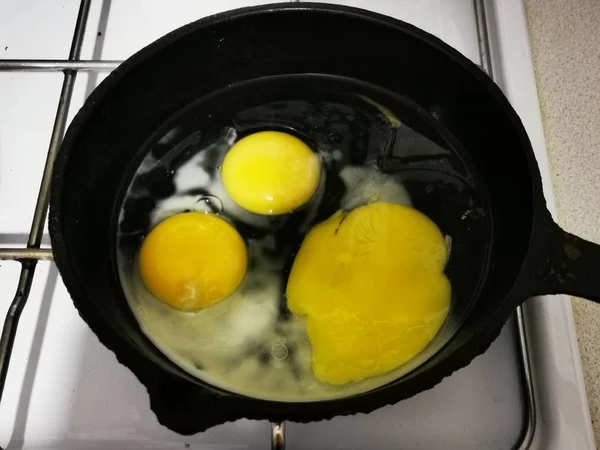 cooking fried eggs from 3 eggs in a black pan