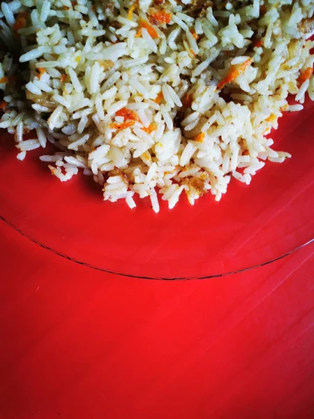 A transparent plate with spicy rice on a red background. Healthy oriental food.