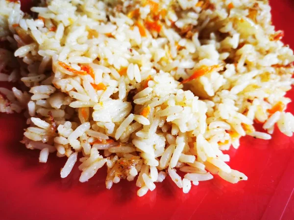 A transparent plate with spicy rice on a red background. Healthy oriental food.