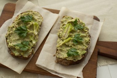 Tahta kesme tahtasındaki ton balıklı kızarmış ekmek ve avokadodan oluşan sağlıklı bir kahvaltı.