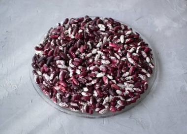 Gri arka planda beyaz ve kırmızı fasulyeler. Fasulye sağlıklı, lezzetli ve tatmin edici bir üründür..